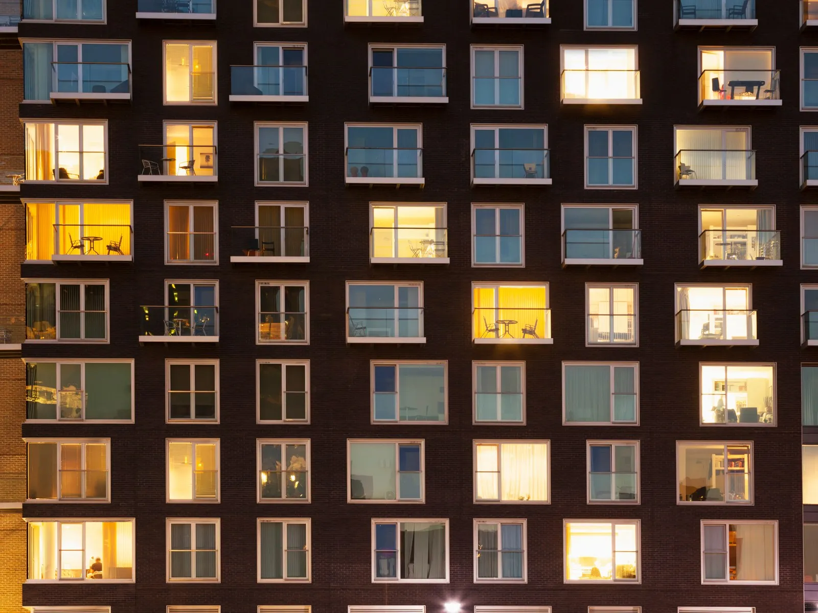 The lit windows of an apartment building in the evening.